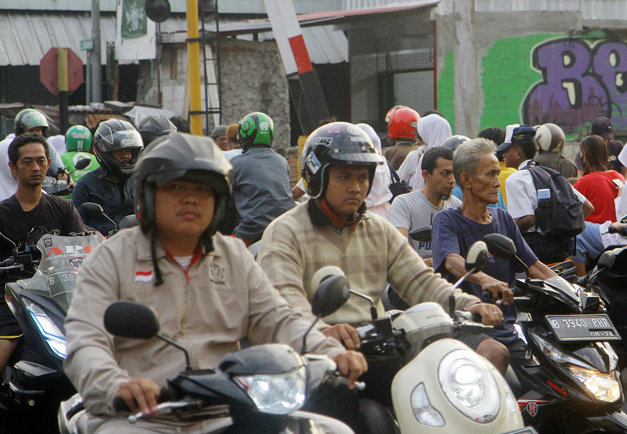 Pengendar motor melintasi pintu kereta di Jalan Menteng Jaya, Jakarta, Rabu (24/7/2024).(BeritaNasional.com/Oke Atmaja)