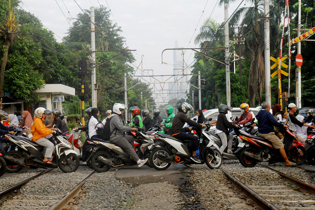 Pengendar motor melintasi pintu kereta di Jalan Menteng Jaya, Jakarta, Rabu (24/7/2024).(BeritaNasional.com/Oke Atmaja)