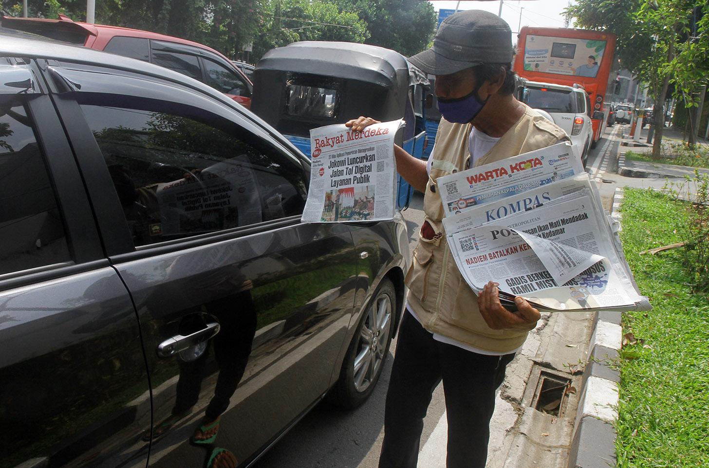 Imron (71) menawarkan koran kepada pembeli di Jalan Pangeran Diponegoro, Jakarta, Senin (3/6/2024).(BeritaNasional.Com/Oke Atmaja)