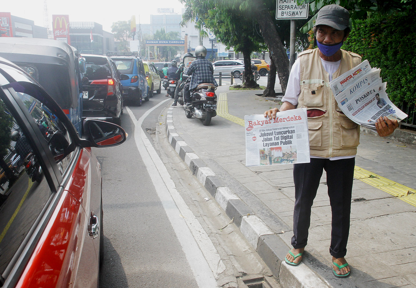 Imron (71) menawarkan koran kepada pembeli di Jalan Pangeran Diponegoro, Jakarta, Senin (3/6/2024).(BeritaNasional.Com/Oke Atmaja)