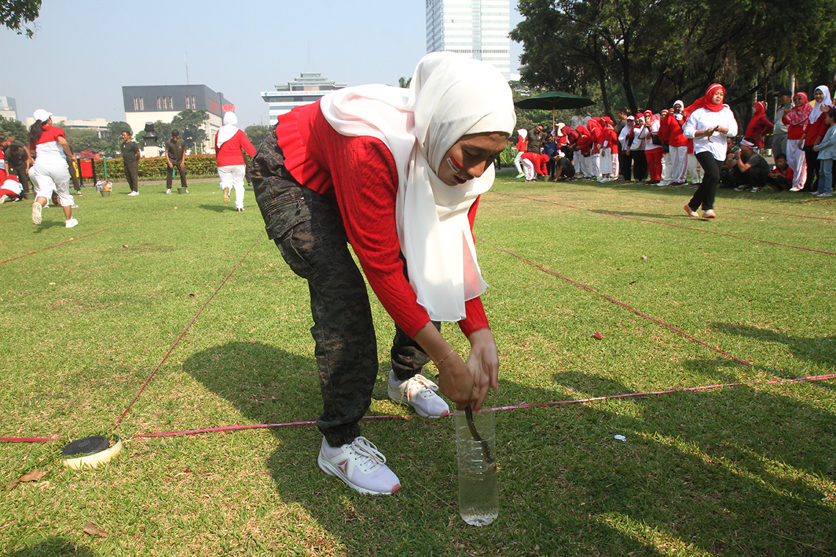 Peserta mengikuti lomba memasukan belut kedalam botol secara estafet dalam rangka memperingati HUT RI ke-79, di Silang Monas, Jakarta, Kamis (15/8/2024).  (BeritaNasional.com/ Oke Atmaja)