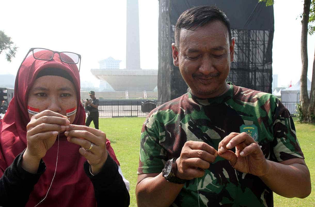 Peserta mengikuti lomba memasukan belut kedalam botol secara estafet dalam rangka memperingati HUT RI ke-79, di Silang Monas, Jakarta, Kamis (15/8/2024).  (BeritaNasional.com/ Oke Atmaja)