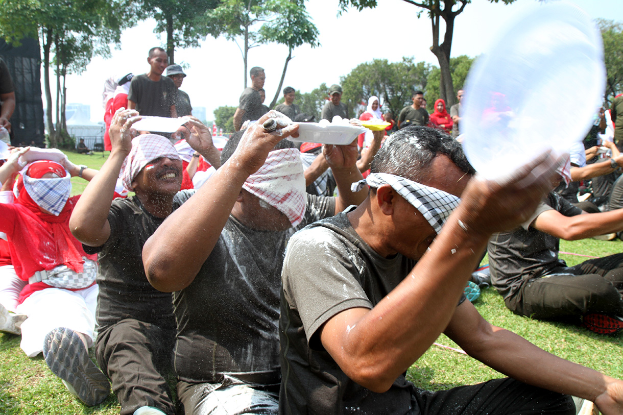 Peserta mengikuti lomba memasukan belut kedalam botol secara estafet dalam rangka memperingati HUT RI ke-79, di Silang Monas, Jakarta, Kamis (15/8/2024).  (BeritaNasional.com/ Oke Atmaja)