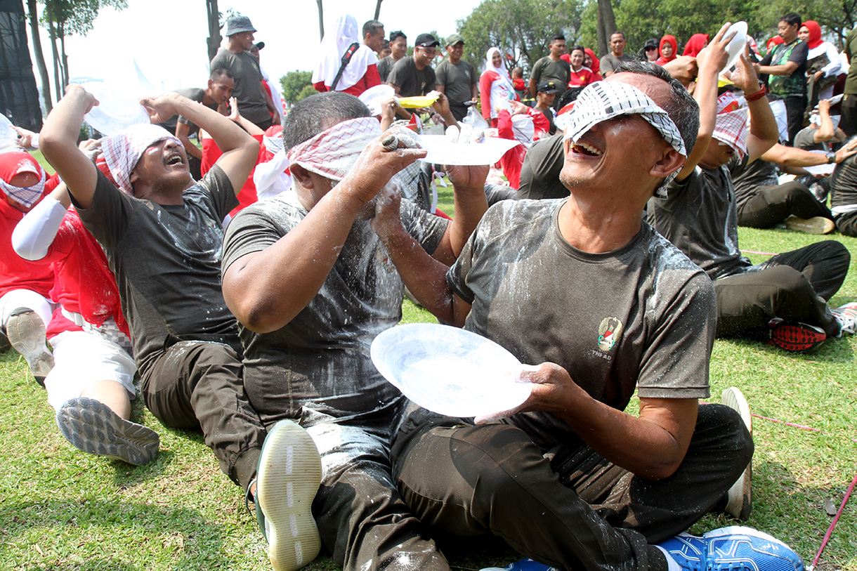 Peserta mengikuti lomba memasukan belut kedalam botol secara estafet dalam rangka memperingati HUT RI ke-79, di Silang Monas, Jakarta, Kamis (15/8/2024).  (BeritaNasional.com/ Oke Atmaja)