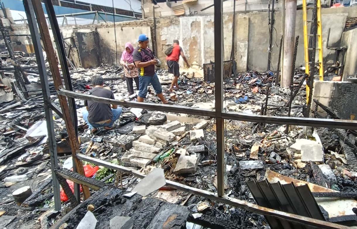 Pedagang mencari barang yang tersisa di kios yang terbakar di kawasan Kalibata, Jakarta, Jumat (12/12/2025).  (Beritanasional.com/Oke Atmaja)