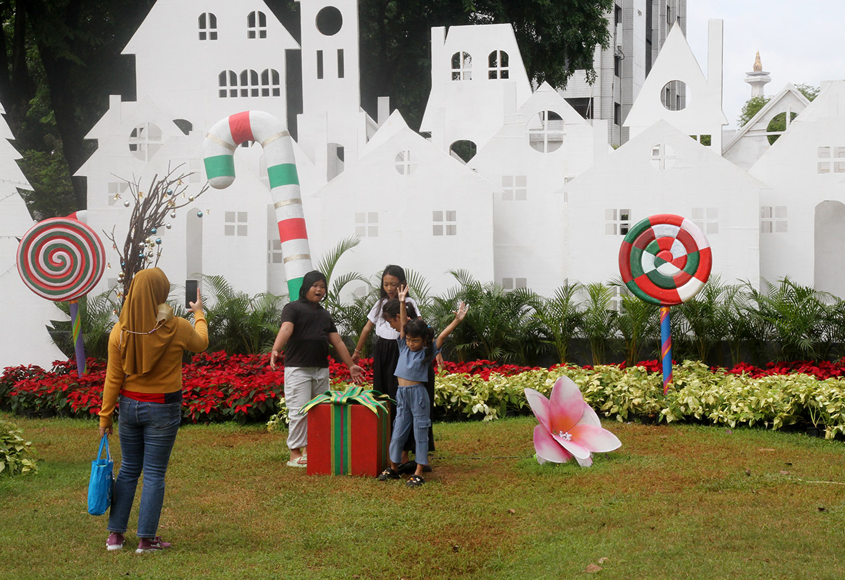 Sejumlah warga bermain dengan latar belakang dekorasi khas Natal di Taman Lapangan Banteng, Jakarta, Rabu (25/12/2024).(BeritaNasional.com/Oke Atmaja)