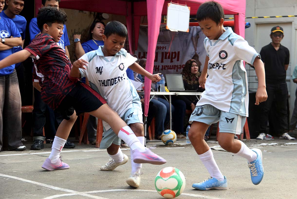 Anak-anak mengikuti pertandingan Turnamen Sepak Bola "Liga Aspal" U-13 di lapangan sederhana kawasan permukiman padat pinggir rel RT 09/RW 08, Menteng Jaya, Jakarta, Sabtu (20/6/2026). (Beritanasional.com/Oke Atmaja)