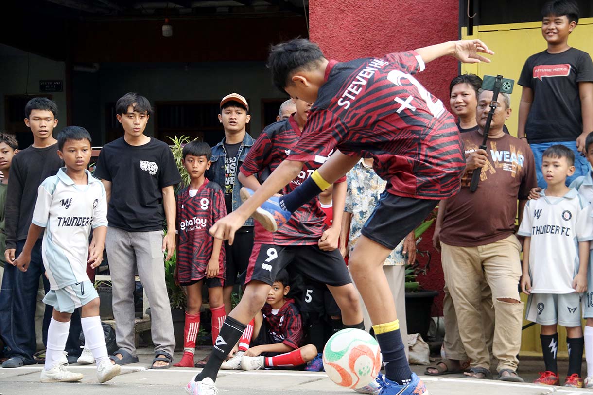 Anak-anak mengikuti pertandingan Turnamen Sepak Bola "Liga Aspal" U-13 di lapangan sederhana kawasan permukiman padat pinggir rel RT 09/RW 08, Menteng Jaya, Jakarta, Sabtu (20/6/2026). (Beritanasional.com/Oke Atmaja)