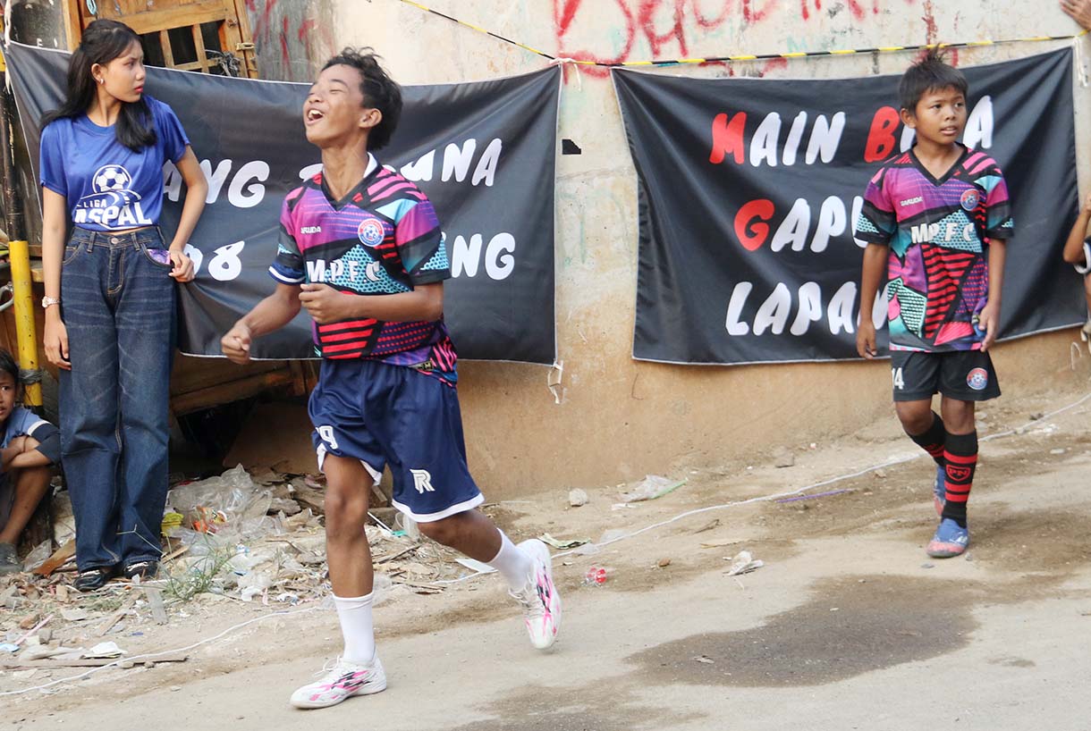 Anak-anak mengikuti pertandingan Turnamen Sepak Bola "Liga Aspal" U-13 di lapangan sederhana kawasan permukiman padat pinggir rel RT 09/RW 08, Menteng Jaya, Jakarta, Sabtu (20/6/2026). (Beritanasional.com/Oke Atmaja)