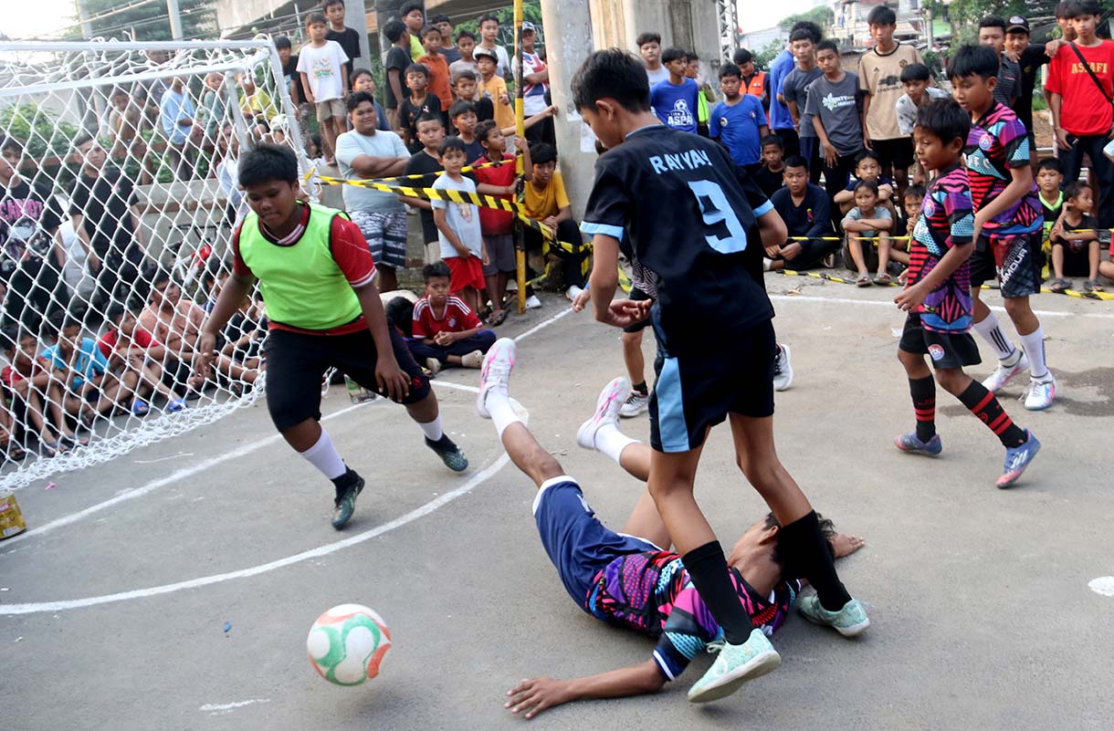 Anak-anak mengikuti pertandingan Turnamen Sepak Bola "Liga Aspal" U-13 di lapangan sederhana kawasan permukiman padat pinggir rel RT 09/RW 08, Menteng Jaya, Jakarta, Sabtu (20/6/2026). (Beritanasional.com/Oke Atmaja)