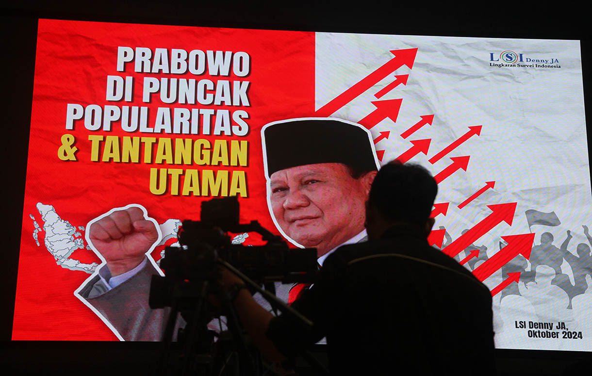 Kameramen berdiri berlatarkan foto Presiden Prabowo Subianto saat pemaparan temuan dan analisis Survei Nasional bertajuk 'Prabowo di Puncak Popularitas & Tantangan Utama' di Jakarta, Selasa (22/10/2024).(BeritaNasional.com/Oke Atmaja)