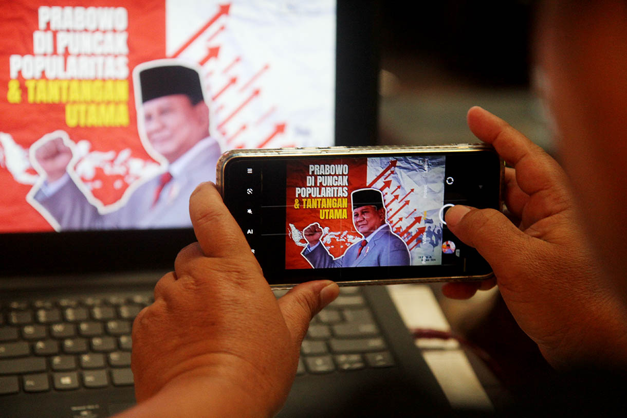 Kameramen berdiri berlatarkan foto Presiden Prabowo Subianto saat pemaparan temuan dan analisis Survei Nasional bertajuk 'Prabowo di Puncak Popularitas & Tantangan Utama' di Jakarta, Selasa (22/10/2024).(BeritaNasional.com/Oke Atmaja)