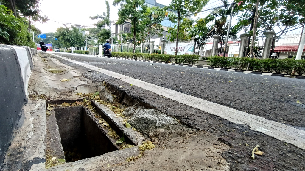 Lubang Drainase tanpa Penutup Besi di Jakarta Kendaraan melintas di samping lubang drainase yang besi penutupnya hilang di Jalan Proklamasi, Jakarta, Minggu (11/5/2025). (Berita nasional.com/ Oke Atmaja)