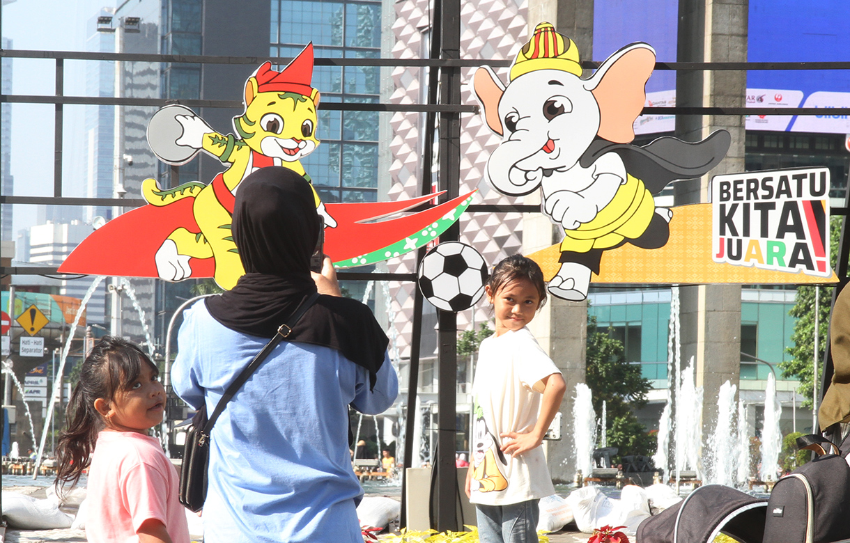 Warga berfoto berlatar belakang maskot PON XXI Tahun 2024 di Bundaran HI, Jakarta, Minggu (8/9/2024). (BeritaNasional.com/ Oke Atmaja)