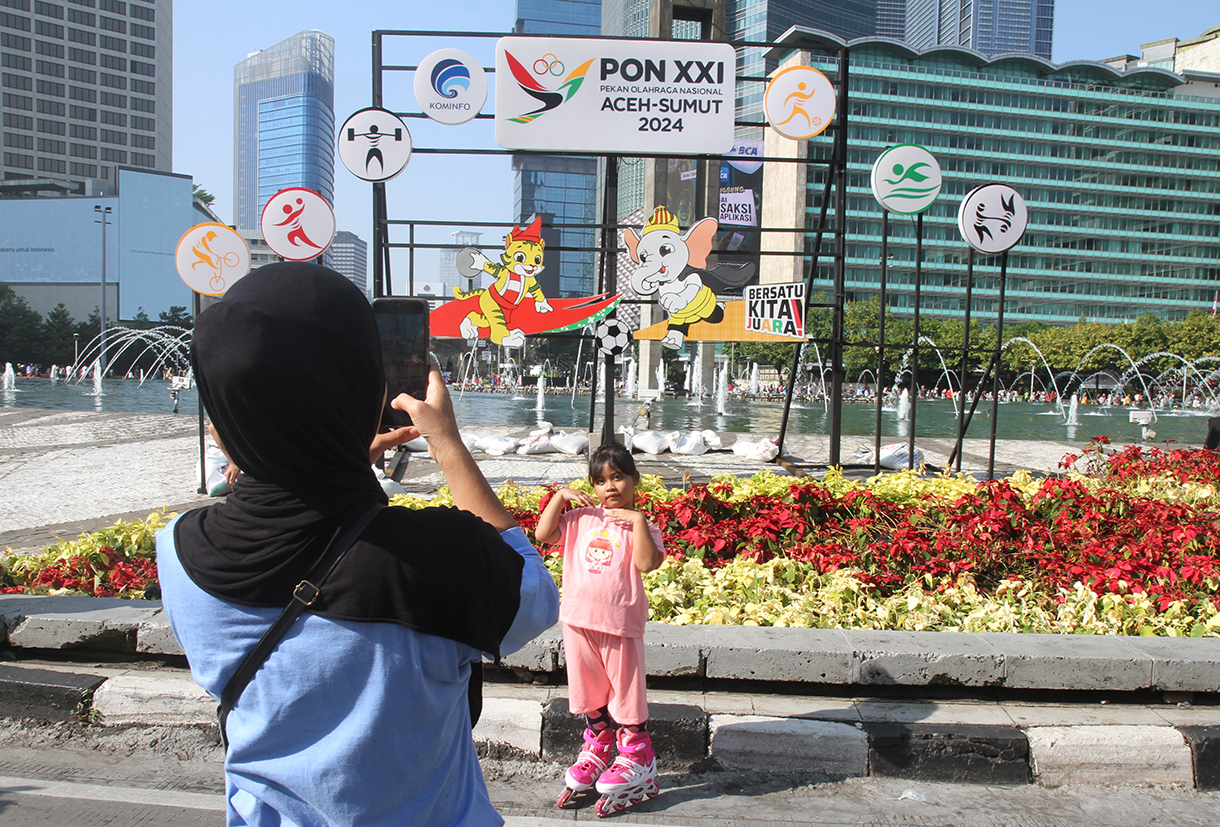 Warga berfoto berlatar belakang maskot PON XXI Tahun 2024 di Bundaran HI, Jakarta, Minggu (8/9/2024). (BeritaNasional.com/ Oke Atmaja)