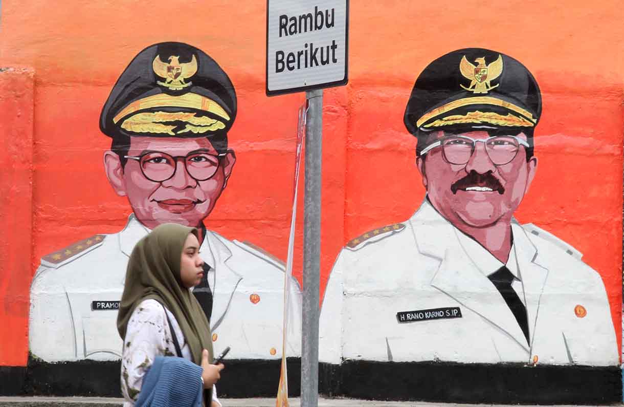 Pedagang melintas di depan mural dengan tema peringatan 500 tahun Jakarta di Jalan Bukit Duri, Jakarta, Sabtu (14/6/2025).(Beritanasional.com/Oke Atmaja)