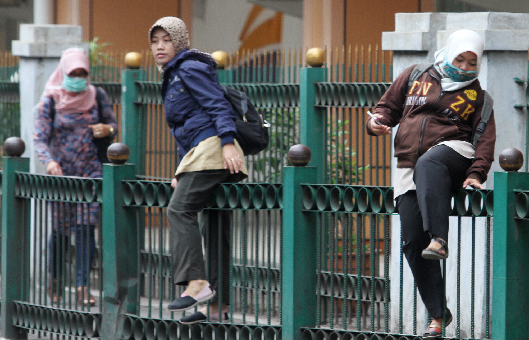 Penumpang KRL melompati pagar pembatas di depan Stasiun Cikini, Jalan Cikini Raya, Jakarta Pusat, Rabu (20/3/2024).  (IndonesiaGlobe/Oke Atmaja)