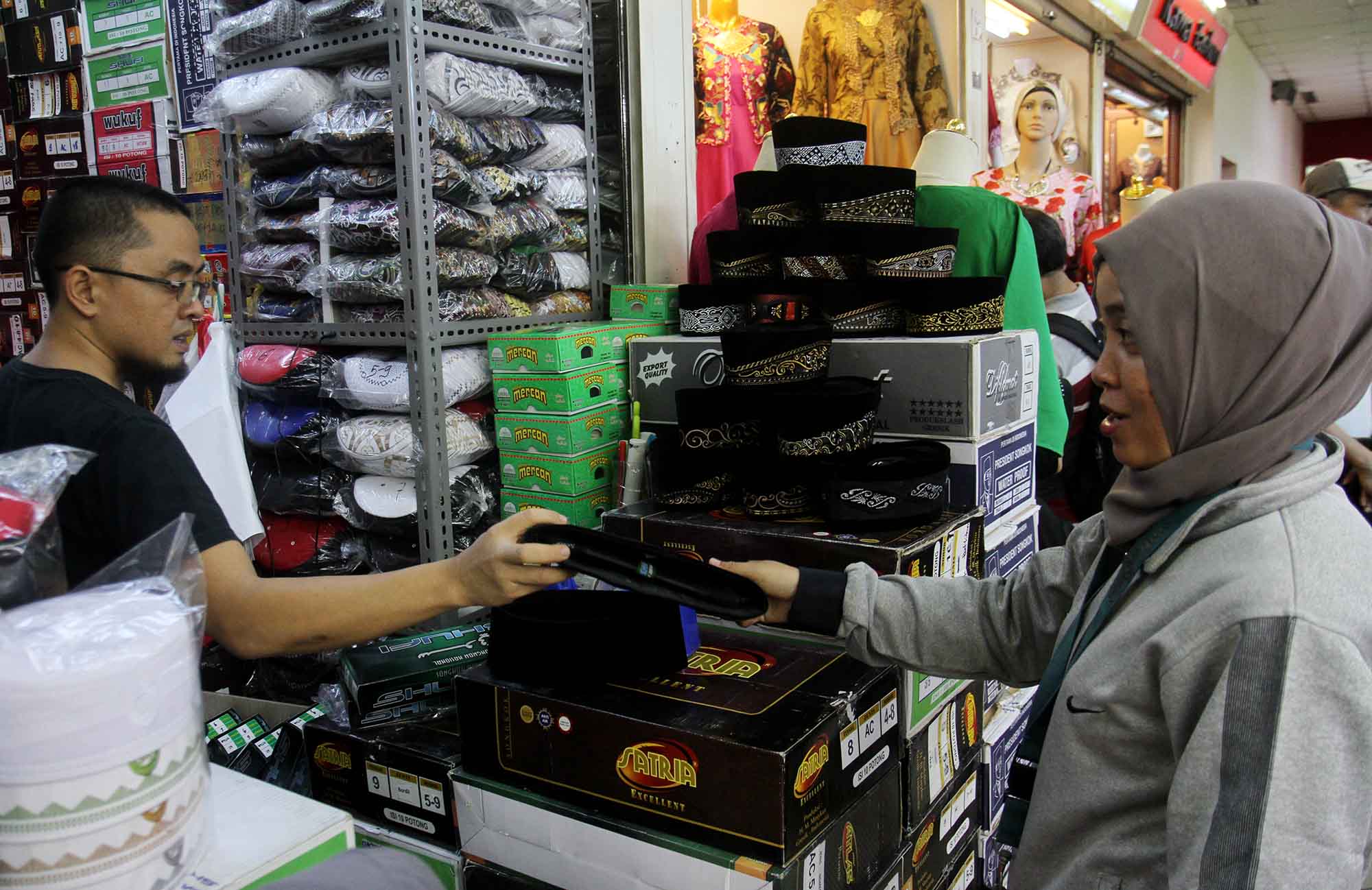 Penjual melayani pembeli peci di Pasar Tanah Abang, Jakarta,Rabu (20/3/2024). (IndonesiaGlobe/Oke Atmaja)