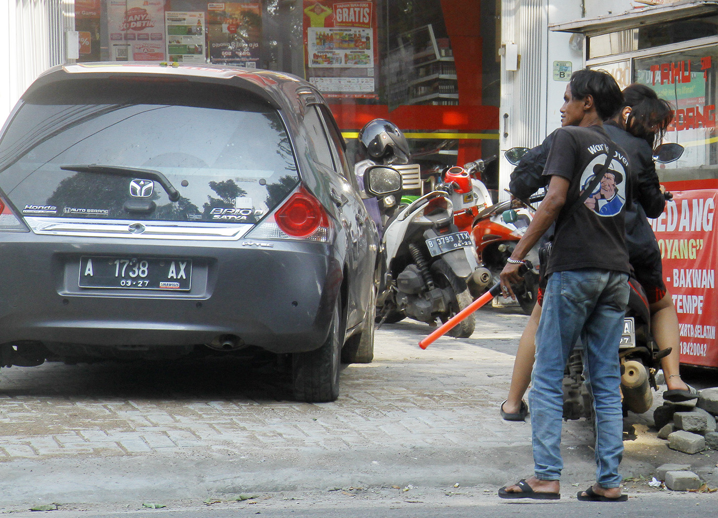 Juru parkir memarkirkan kendaraan di salah satu minimarket di kawasan Jakarta, Senin (13/5/2024).  (BeritaNasional.com/Oke Atmaja)