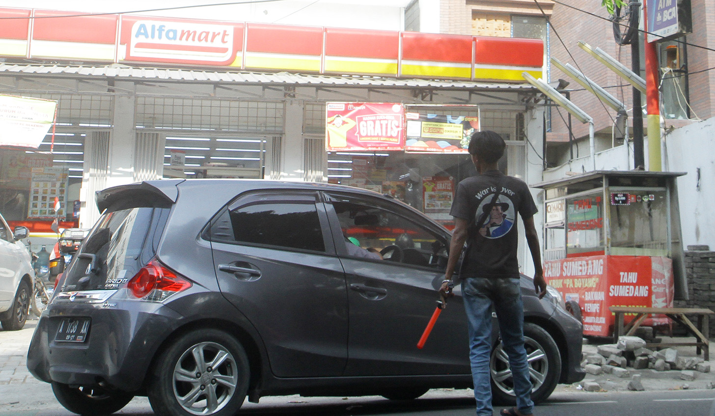 Juru parkir memarkirkan kendaraan di salah satu minimarket di kawasan Jakarta, Senin (13/5/2024).  (BeritaNasional.com/Oke Atmaja)