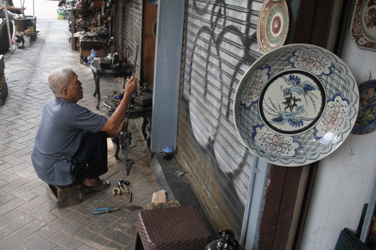 Penjual membersihkan barang dagangannya di Sentra Penjualan Barang Antik Jalan Surabaya, Menteng, Jakarta, Kamis (21/8/2025).  (Beritanasional.com/Oke Atmaja)