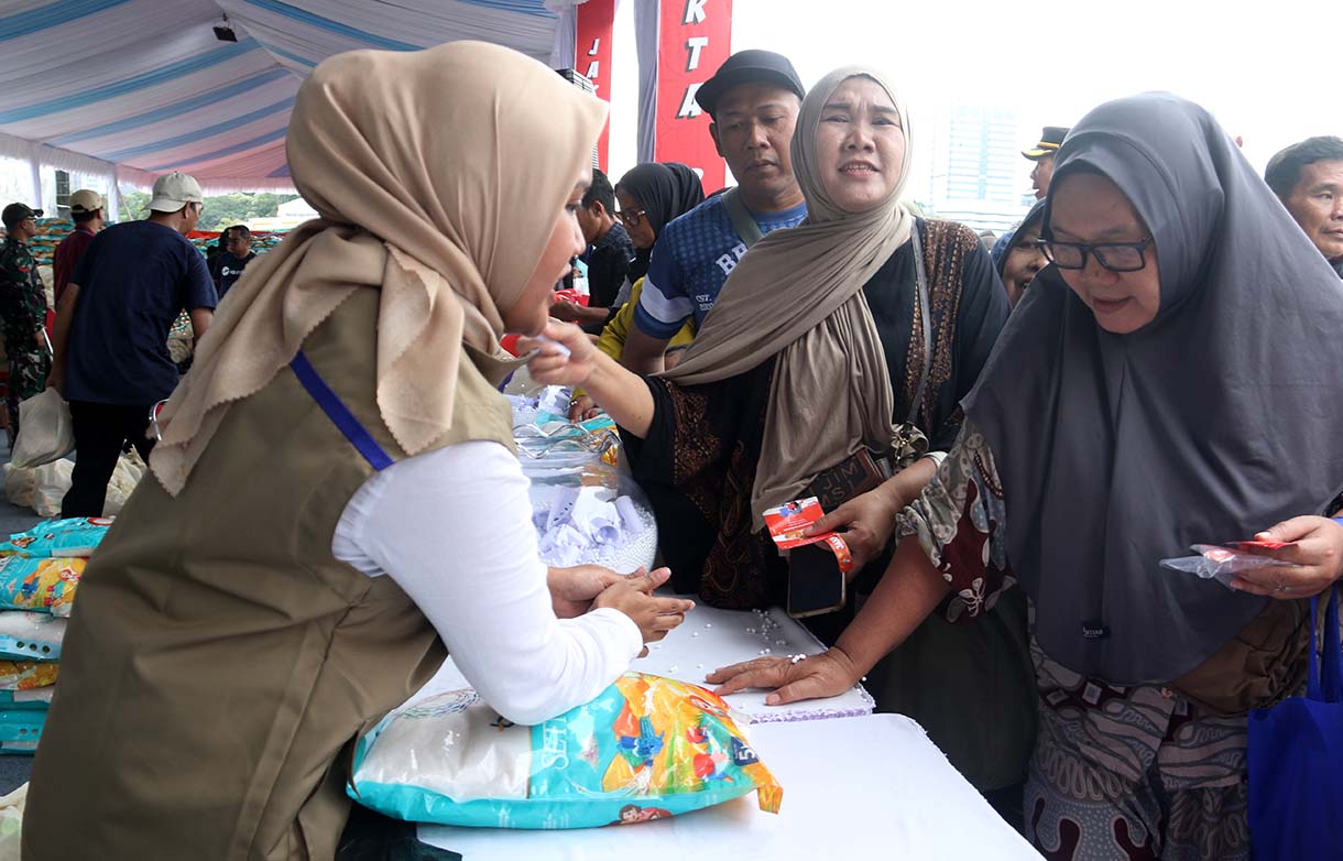 Petugas melayani warga yang mengambil paket sembako pada Pasar Murah untuk Rakyat di kawasan Monas, Jakarta, Sabtu (28/3/2026).  (Beritanasional.com/Oke Atmaja)