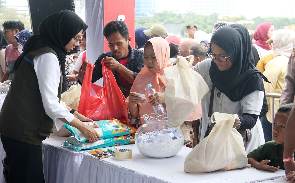 Petugas melayani warga yang mengambil paket sembako pada Pasar Murah untuk Rakyat di kawasan Monas, Jakarta, Sabtu (28/3/2026).  (Beritanasional.com/Oke Atmaja)
