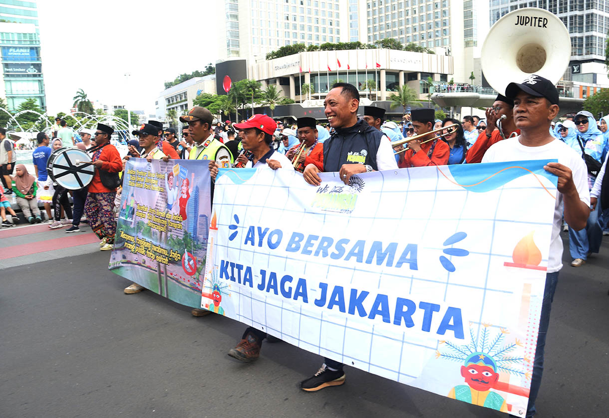 Sejumlah peserta membawa spanduk berisi imbauan untuk menjaga kebersihan dan ketertiban saat mengikuti pawai pada Hari Bebas Kendaraan Bermotor (HBKB) di kawasan Bundaran HI, Jakarta Pusat, Minggu (16/11/2025).(Beritanasional.com/Oke Atmaja)
