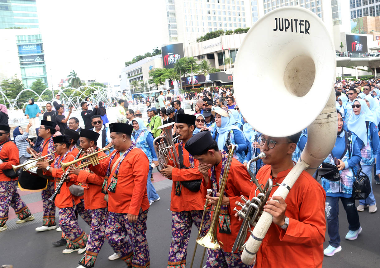 Sejumlah peserta membawa spanduk berisi imbauan untuk menjaga kebersihan dan ketertiban saat mengikuti pawai pada Hari Bebas Kendaraan Bermotor (HBKB) di kawasan Bundaran HI, Jakarta Pusat, Minggu (16/11/2025).(Beritanasional.com/Oke Atmaja)