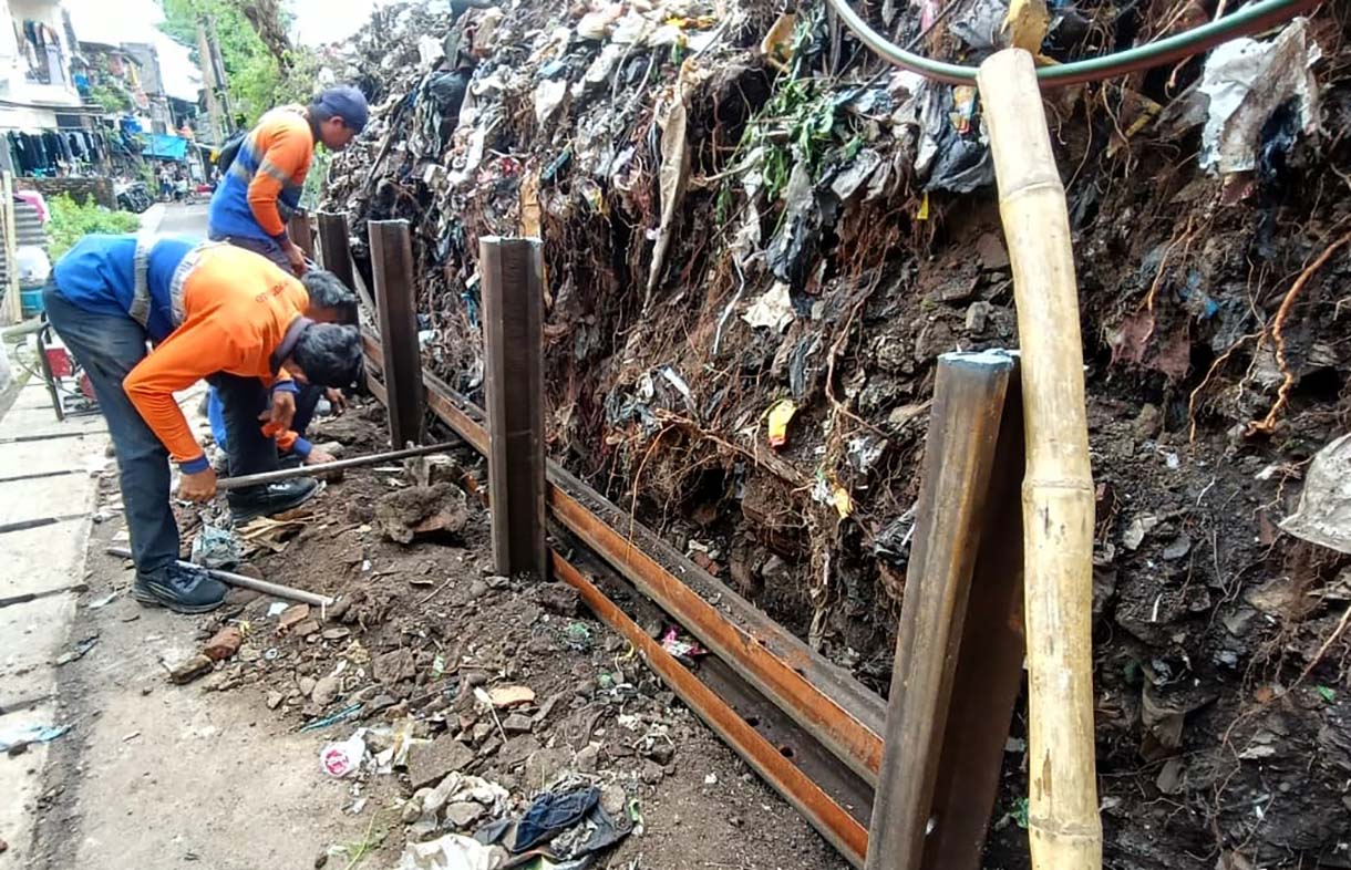 Petugas memasang besi rel kereta api untuk menahan tanah longsor di Kawasan Menteng, Jakarta Pusat, Minggu (23/11/2025).  (Beritanasional.com/Oke Atmaja)