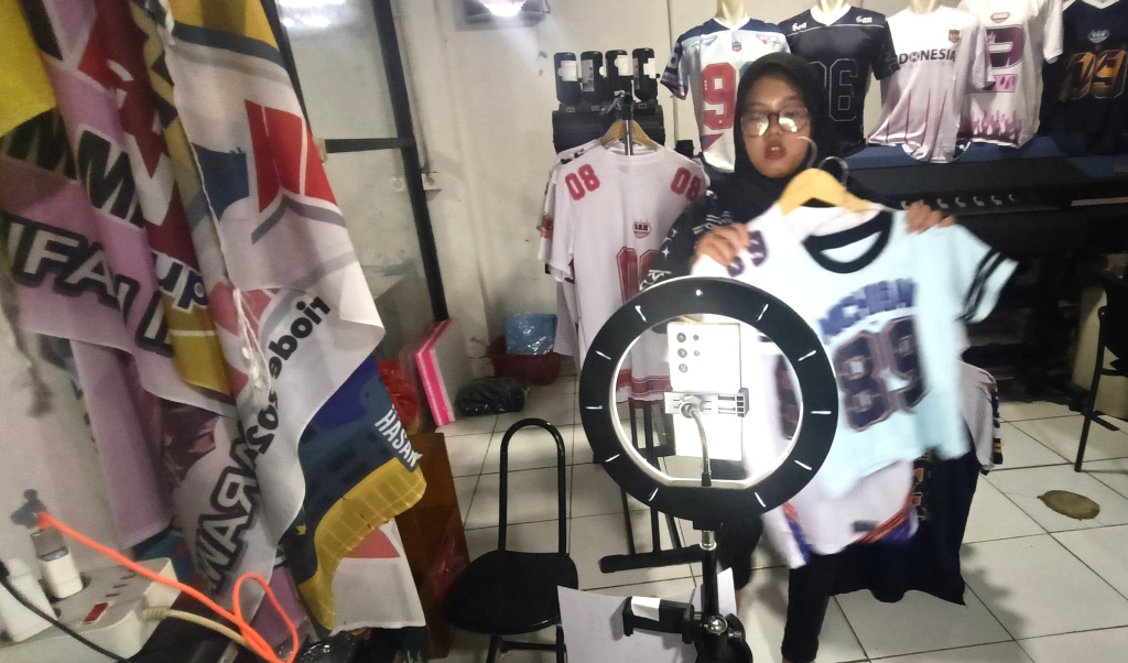 Pemberlakuan Pemungutan Pajak bagi Penjual Daring Pelaku UMKM menjual kaos melalui siaran langsung di bengkel kerja Sinergi Adv di kawasan Srengseng Sawah, Jakarta Selatan Selasa (15/7/2025). (Beritanasional.com/Oke Atmaja)