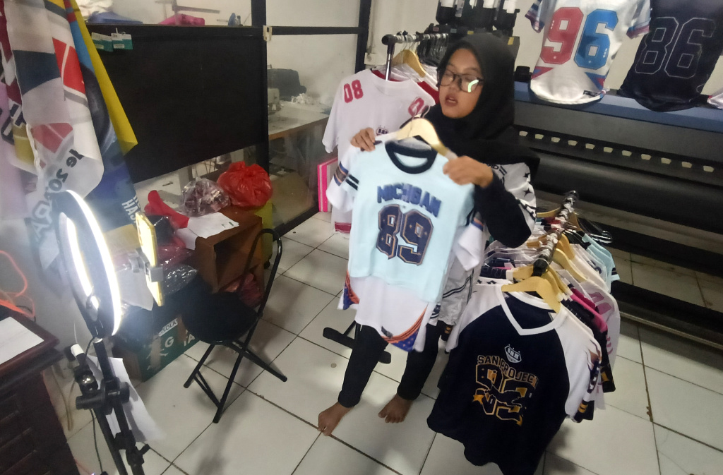 Pemberlakuan Pemungutan Pajak bagi Penjual Daring Pelaku UMKM menjual kaos melalui siaran langsung di bengkel kerja Sinergi Adv di kawasan Srengseng Sawah, Jakarta Selatan Selasa (15/7/2025). (Beritanasional.com/Oke Atmaja)
