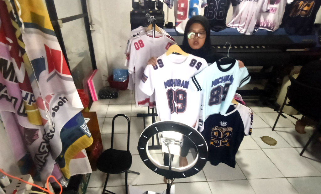 Pemberlakuan Pemungutan Pajak bagi Penjual Daring Pelaku UMKM menjual kaos melalui siaran langsung di bengkel kerja Sinergi Adv di kawasan Srengseng Sawah, Jakarta Selatan Selasa (15/7/2025). (Beritanasional.com/Oke Atmaja)
