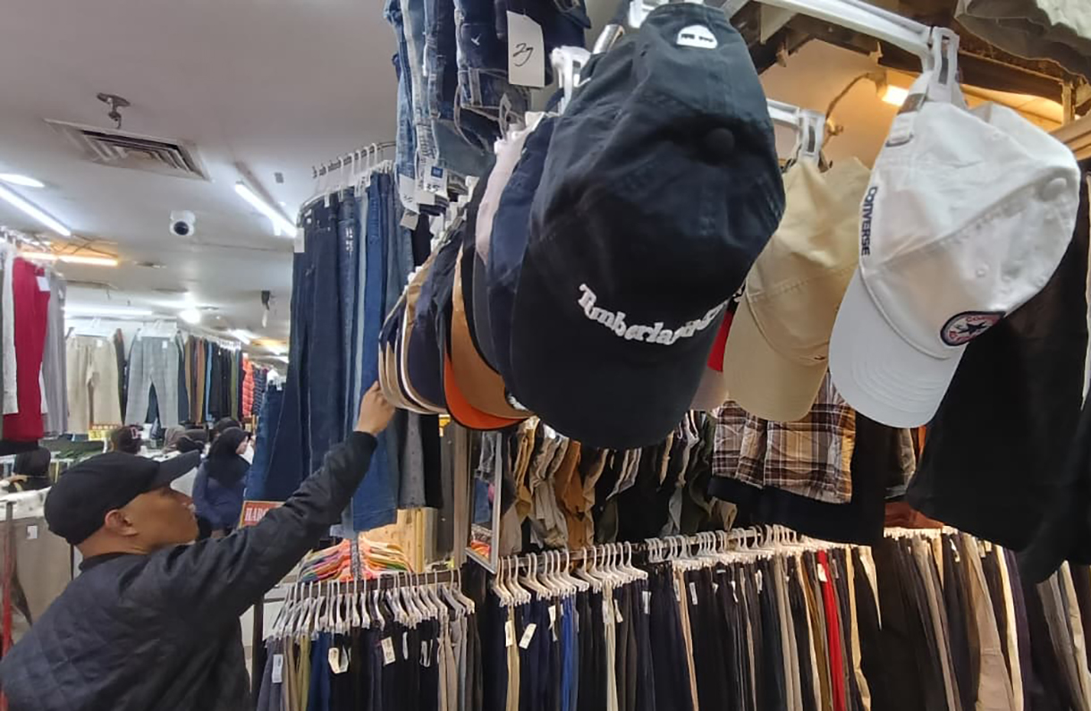Calon pembeli memilih pakaian bekas yang dijual di salah satu toko di Pasar Senen, Jakarta, Selasa (30/12/2025). (Beritanasional.com/Oke Atmaja)