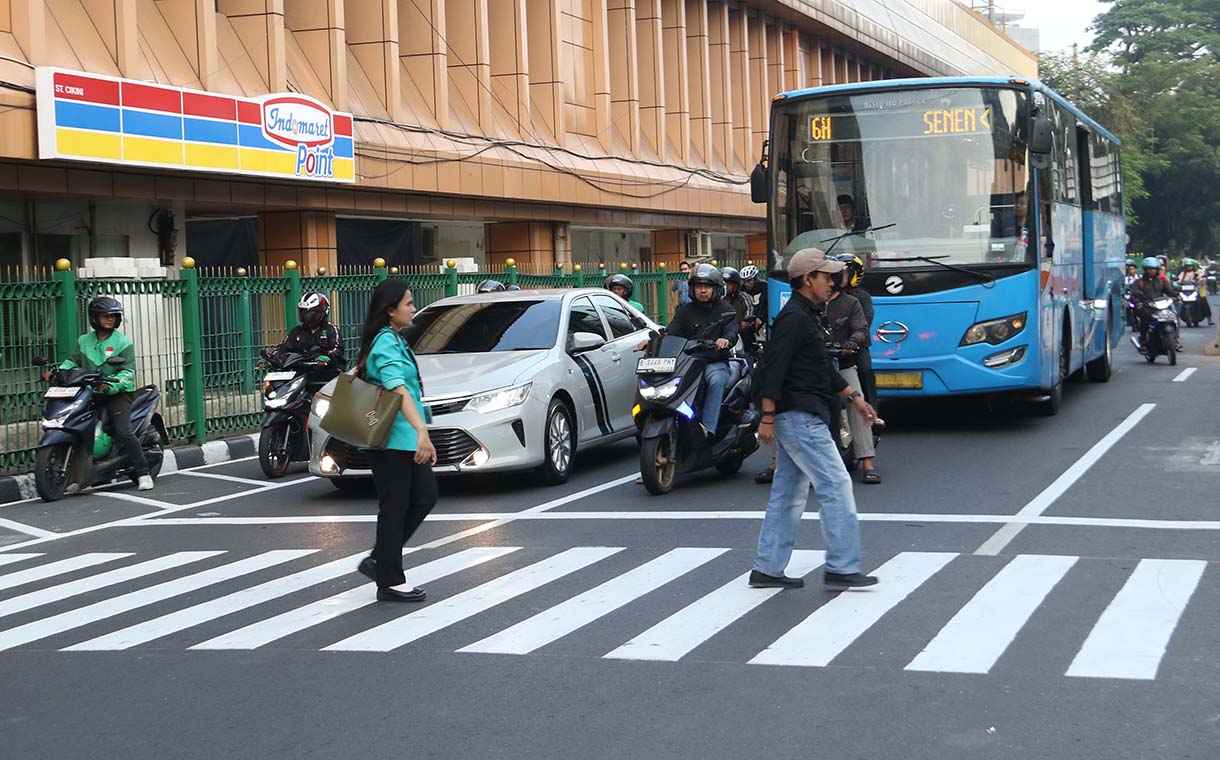 Warga menyeberang jalan menggunakan pelican crossing di sisi timur Stasiun Cikini, Jakarta, Senin (29/9/2025). (Beritanasional.com/Oke Atmaja)