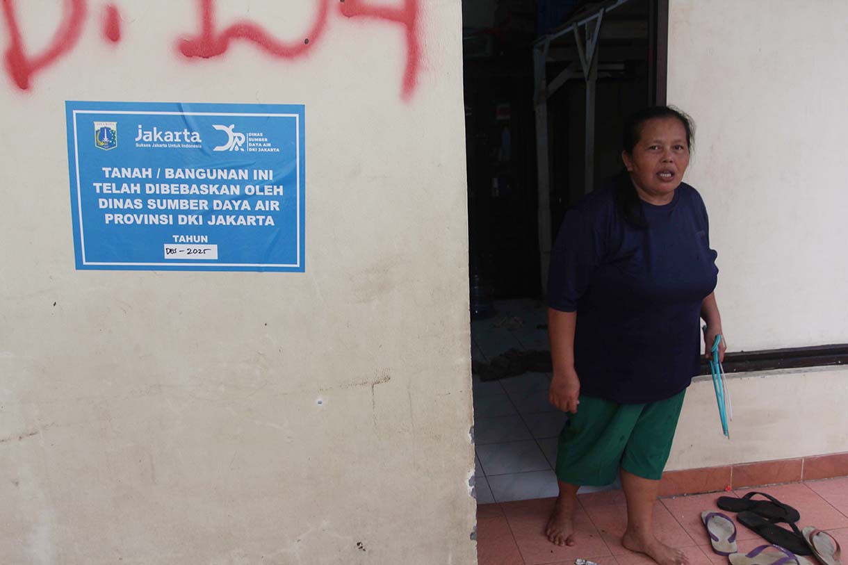 Warga melintas didekat bangunan rumah yang tertempel stiker tanda pembebasan lahan di Cawang, Jakarta, Senin (3/2/2026).(Beritanasional.com/Oke Atmaja)
