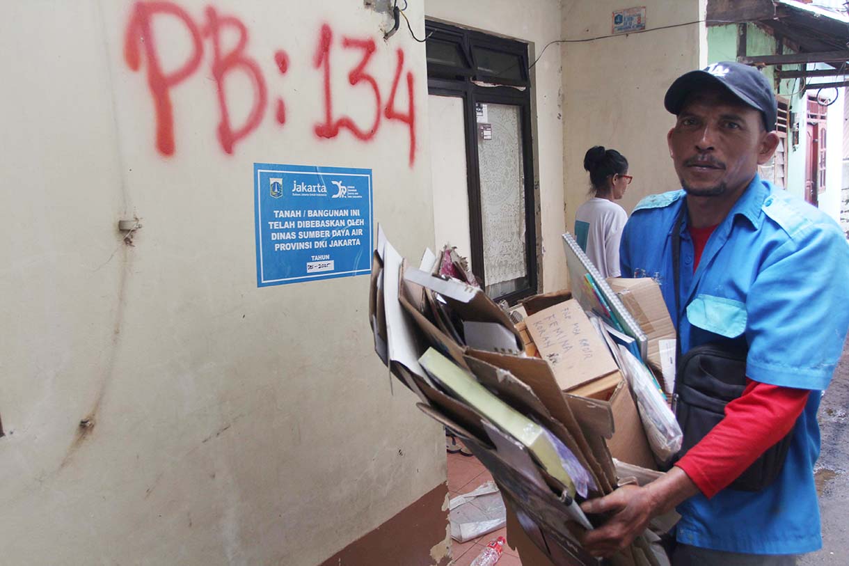 Warga melintas didekat bangunan rumah yang tertempel stiker tanda pembebasan lahan di Cawang, Jakarta, Senin (3/2/2026).(Beritanasional.com/Oke Atmaja)