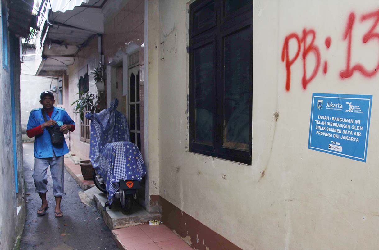 Warga melintas didekat bangunan rumah yang tertempel stiker tanda pembebasan lahan di Cawang, Jakarta, Senin (3/2/2026).(Beritanasional.com/Oke Atmaja)