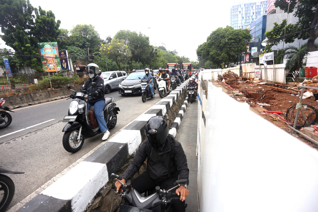 Sejumlah kendaraan sepeda motor melintasi dekat kawasan proyek pembangunan Jembatan Penyebrangan Orang (JPO) di Jalan Warung Jati Barat, Pejaten, Jakarta Selatan, Rabu (8/7/2026). (Beritanasional.com/Oke Atmaja)