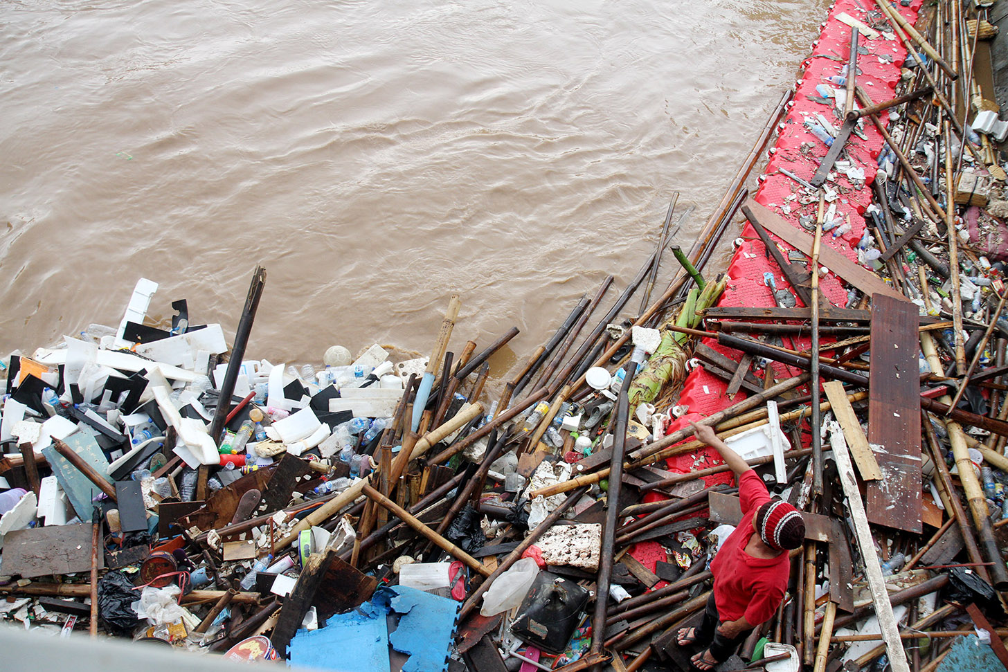 Pemulung mencari sampah plastik untuk dijual kembali di pintu air Manggarai, Jakarta,Selasa (2/7/2024).(BeritaNasional.com/Oke Atmaja)