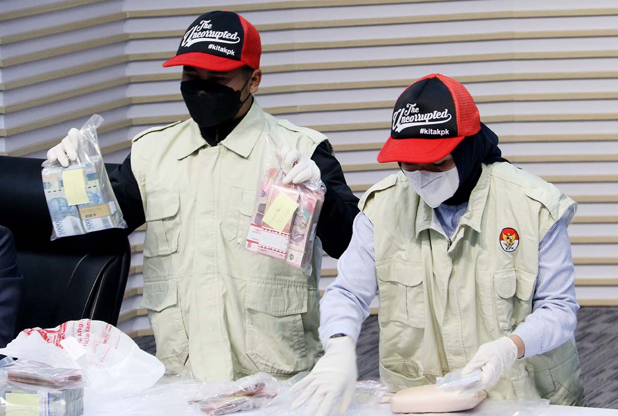Dua petugas yang menunjukkan barang bukti uang tunai dan logam mulia dari kasus dugaan suap dan gratifikasi di Pemerintah Kabupaten Lampung Tengah. (Beritanasional.com/Oke Atmaja)