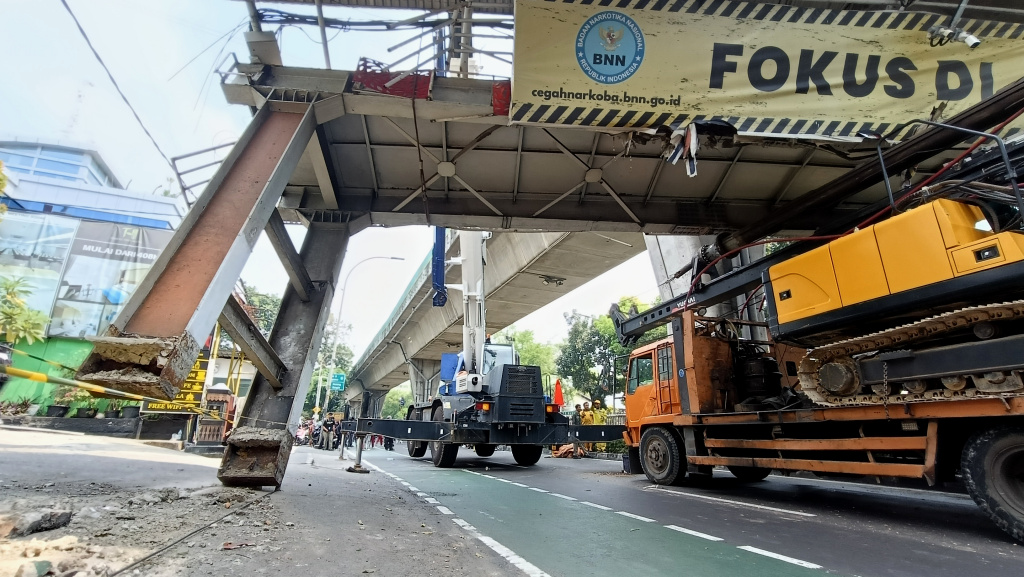 Petugas mengamankan lokasi Jembatan Penyeberangan Orang (JPO) di Jalan Kapten Tendean, Jakarta Selatan, Selasa (14/7/2026). (Beritanasional.com/Oke Atmaja)
