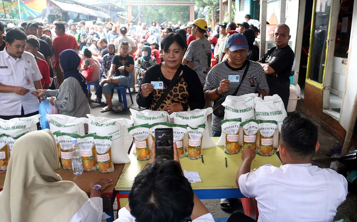 Petugas memberikan beras saat pendistribusian bantuan pangan berupa beras dan minyak goreng, di Balai RW 03 Menteng, Jakarta, Rabu (10/6/2026).  (Beritanasional.com/Oke Atmaja)