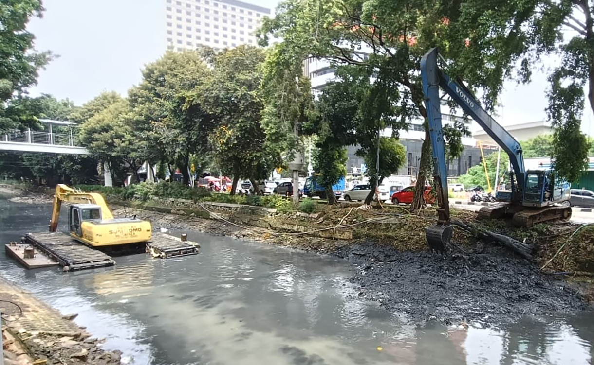 Pekerja menggunakan alat berat mengeruk lumpur endapan Kali Ciliwung kecil di kawasan Kuningan, Jakarta, Minggu (18/8/2026).  (Beritanasional.com/Oke Atmaja)