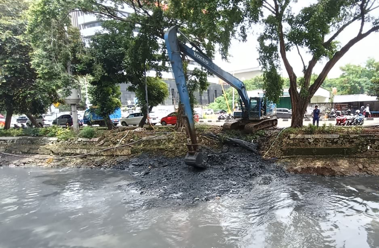 Pekerja menggunakan alat berat mengeruk lumpur endapan Kali Ciliwung kecil di kawasan Kuningan, Jakarta, Minggu (18/8/2026).  (Beritanasional.com/Oke Atmaja)