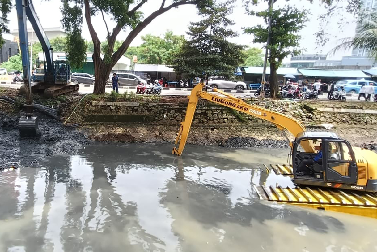 Pekerja menggunakan alat berat mengeruk lumpur endapan Kali Ciliwung kecil di kawasan Kuningan, Jakarta, Minggu (18/8/2026).  (Beritanasional.com/Oke Atmaja)