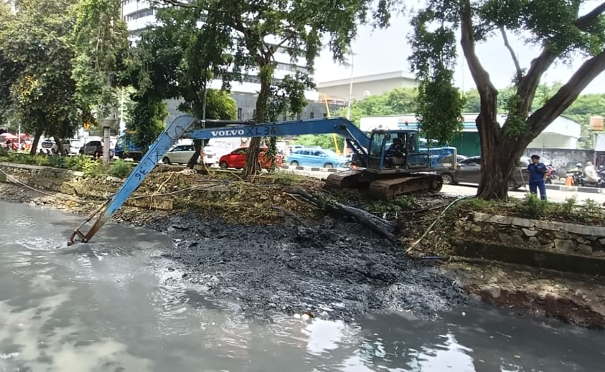 Pekerja menggunakan alat berat mengeruk lumpur endapan Kali Ciliwung kecil di kawasan Kuningan, Jakarta, Minggu (18/8/2026).  (Beritanasional.com/Oke Atmaja)