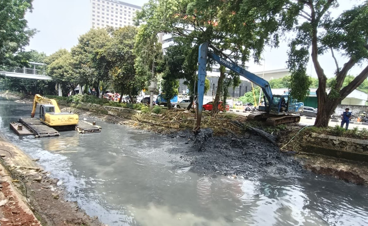 Pekerja menggunakan alat berat mengeruk lumpur endapan Kali Ciliwung kecil di kawasan Kuningan, Jakarta, Minggu (18/8/2026).  (Beritanasional.com/Oke Atmaja)