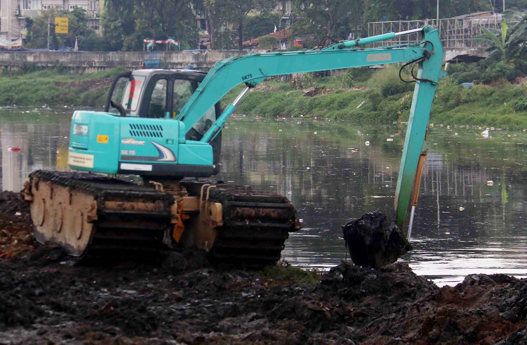 Petugas mengoperasikan alat berat untuk mengeruk lumpur di Sungai Ciliwung, Jakarta, Jumat, (30/8/2024).  (BeritaNasional.com/ Oke Atmaja)