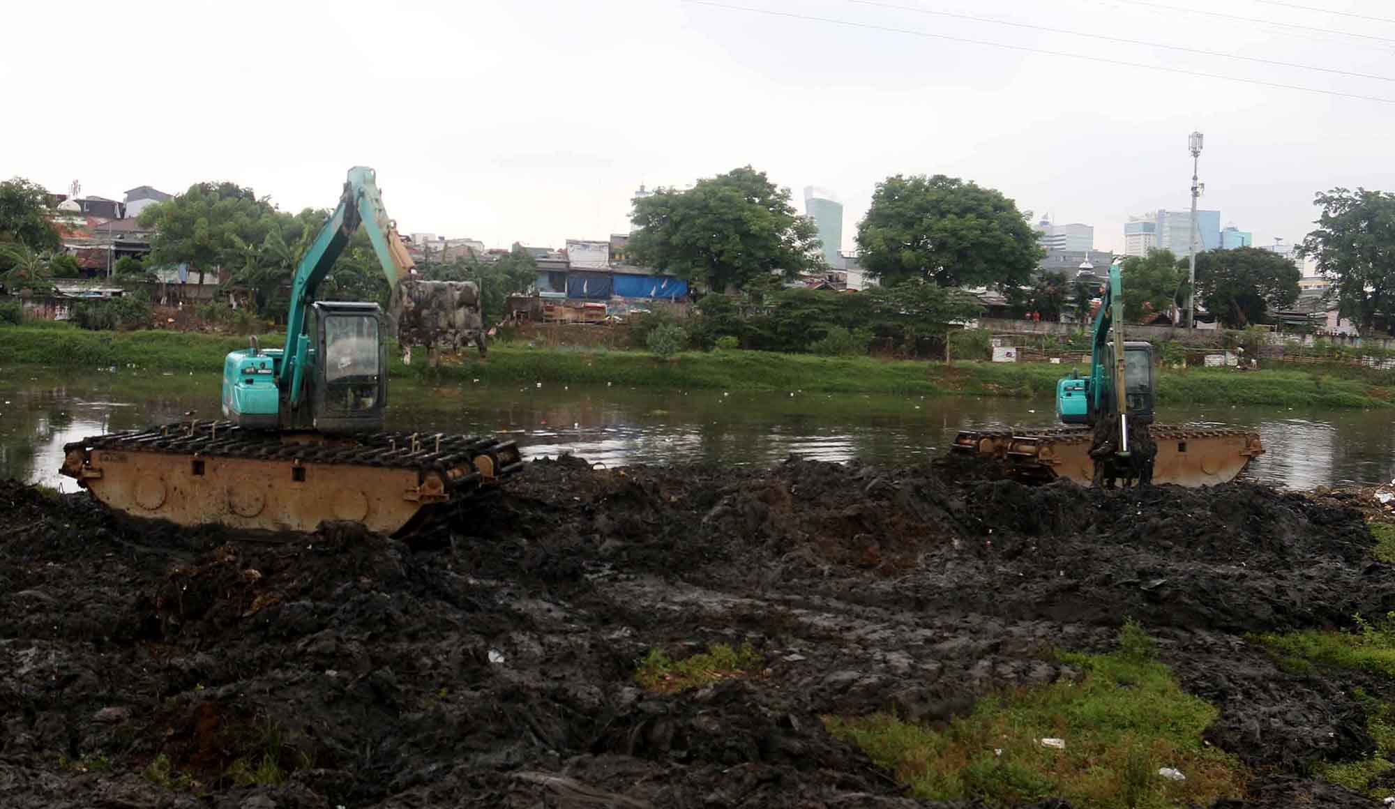 Petugas mengoperasikan alat berat untuk mengeruk lumpur di Sungai Ciliwung, Jakarta, Jumat, (30/8/2024).  (BeritaNasional.com/ Oke Atmaja)